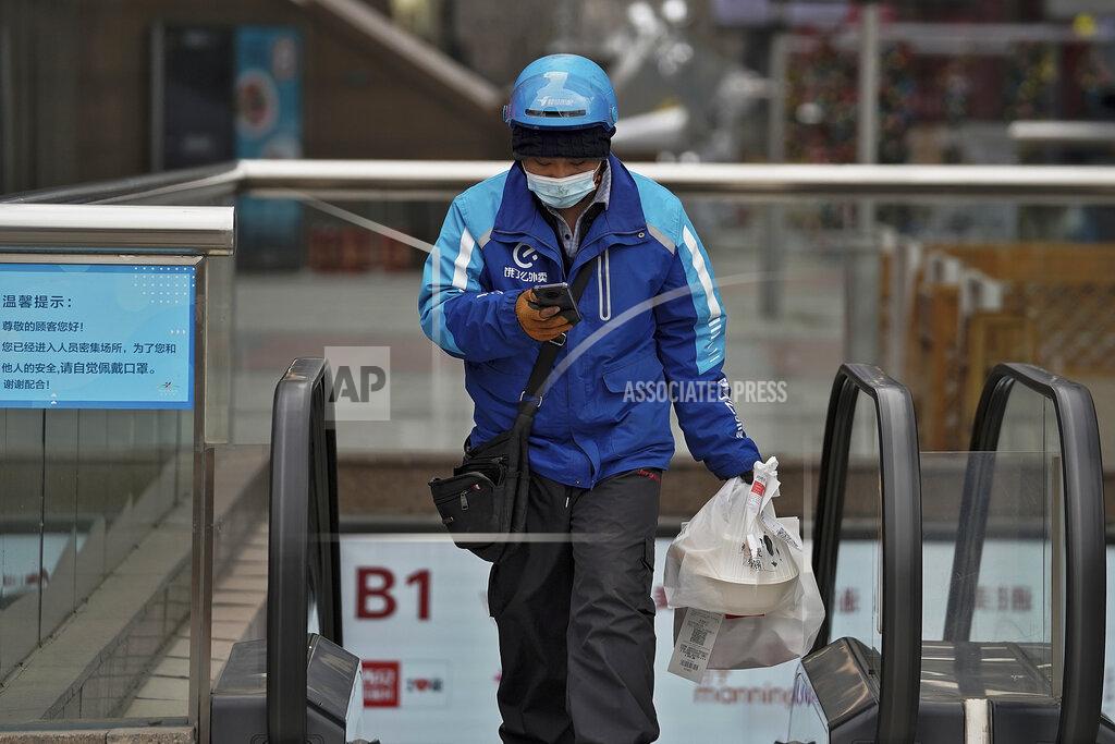 Andy Wong A food delivery worker wearing a face mask to help curb the spread of the coronavirus prepares to deliver foods for his customers at a shopping mall in Beijing on Thursday, Jan. 14, 2021. The e-commerce workers and delivery people who kept China fed during the pandemic, making their billionaire bosses even richer, are so unhappy with their pay and treatment that one just set himself on fire in protest. (AP Photo/Andy Wong)