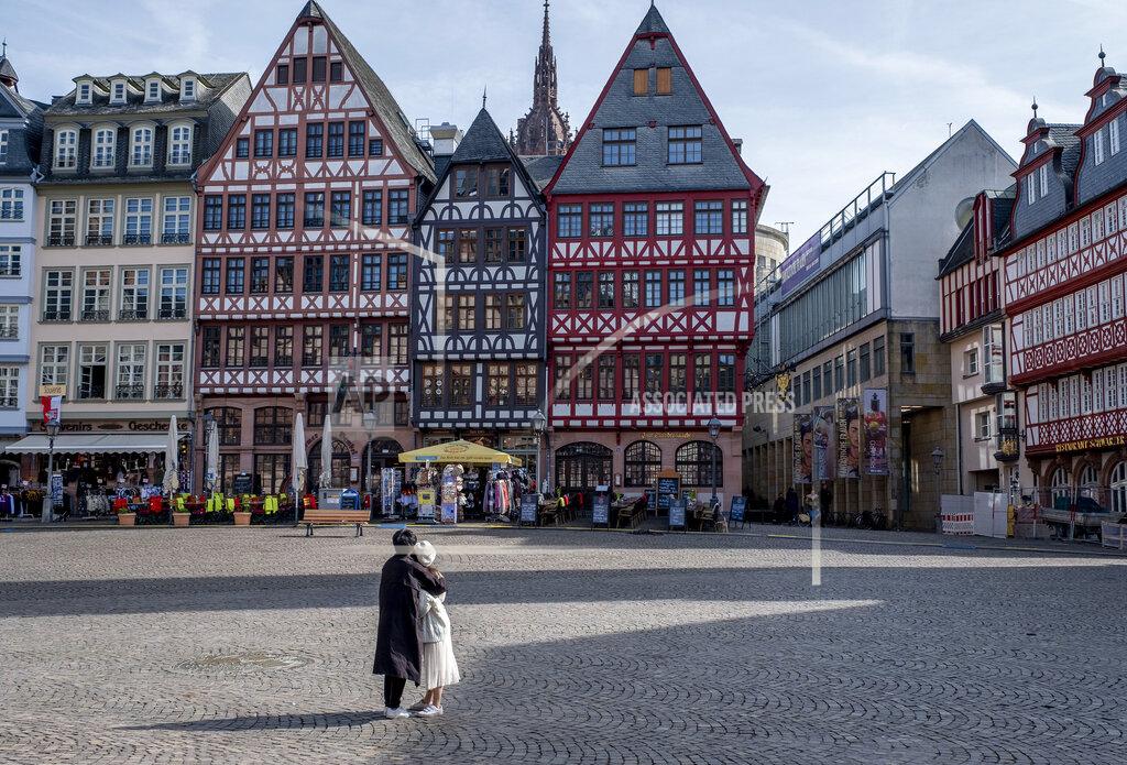 Michael Probst FILE - In this March 15, 2020 file photo, an Asian couple looks at timberframe houses at the almost empty Roemerberg square, the main tourist spot in Frankfurt, Germany. More than 50,000 people have died after contracting COVID-19 in Germany, a number that has risen swiftly over recent weeks as the country has struggled to bring down infection figures. (AP Photo/Michael Probst, File)