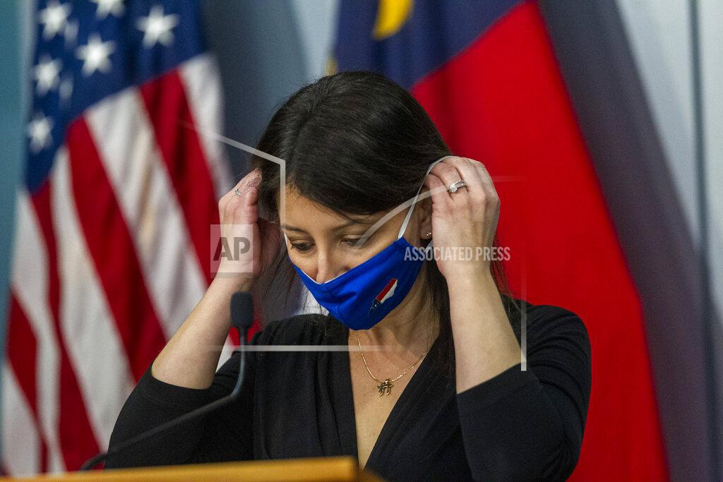 Travis Long Secretary of the NC Department Health and Human Services Dr. Mandy Cohen puts on a a mask after speaking during a briefing on North Carolina's coronavirus pandemic response Wednesday, Jan. 27, 2021 at the NC Emergency Operations Center in Raleigh.(Travis Long/The News & Observer via AP)