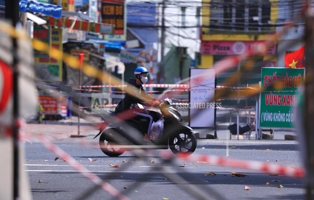 Hau Dinh A man rides a scooter past road barricades made from scaffoldings and cordon tapes in Vung Tau, Vietnam, Monday, Sept. 20, 2021. In Vung Tau, just outside Ho Chi Minh city, streets are sealed and checkpoints are set up to control the movement of people. Barbed wire, door panels, steel sheets, chairs and tables are among materials being used to fence up alleys and isolate neighborhoods.(AP Photo/Hau Dinh)