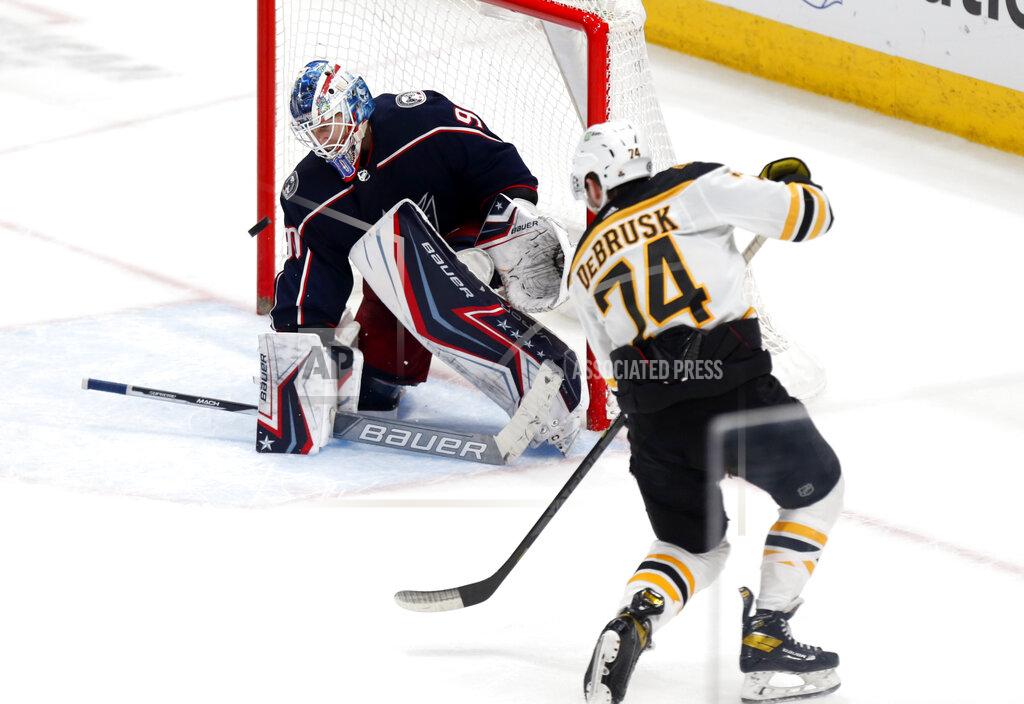Paul Vernon Boston Bruins forward Jake DeBrusk, right scores the winning goal past Columbus Blue Jackets goalie Elvis Merzlikins in an overtime period of an NHL hockey game in Columbus, Ohio, Monday, April 4, 2022. (AP Photo/Paul Vernon)