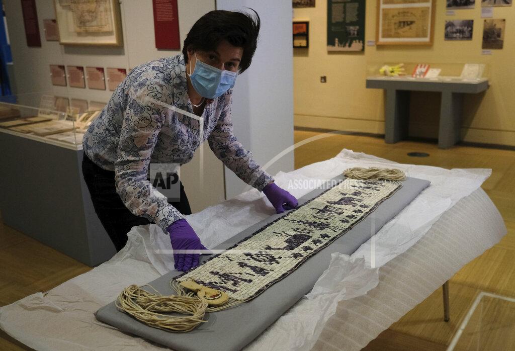 Alastair Grant Co-curator Jo Loosemore looks up to the camera as she examines a recently created wampum belt made by members of the Wampanoag Native America people, after its unpacking and prior to it going on display in Southampton, England, Thursday, Aug. 13, 2020. On the 400th anniversary of the Mayflower voyage, commemorations are focusing on both the Pilgrim settlers and the Native people whose lives were transformed by their arrival. An exhibition in England focuses on one casualty of colonization: a wampum belt taken from the Wampanoag people to England in the 17th century, and then lost. (AP Photo/Alastair Grant)