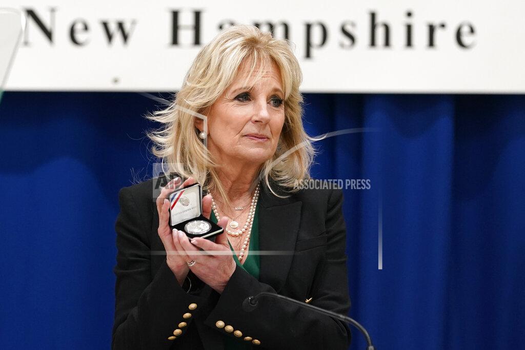 Susan Walsh First lady Jill Biden holds a Christa McAuliffe commemorative coin she received as she speaks at Christa McAuliffe School in Concord, N.H., Wednesday, March 17, 2021, to pay tribute to the New Hampshire woman chosen 35 years ago to be America's "Teacher in Space."(AP Photo/Susan Walsh, Pool)