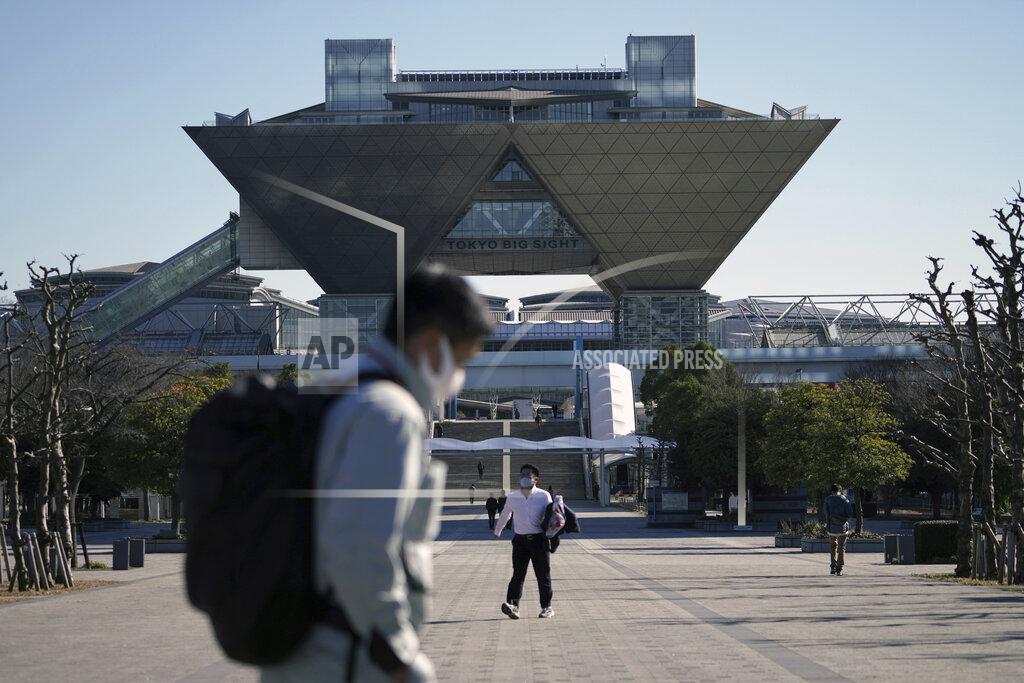Eugene Hoshiko People walk by Tokyo International Exhibition Centre (Tokyo Big Sight) where IBC (International Broadcast Centre) and MPC (Main Press Centre) for Tokyo 2020 Olympics and Paralympics will locate in Tokyo Wednesday, Jan. 20, 2021. The postponed Tokyo Olympics are to open in just six months. Local organizers and the International Olympic Committee say they will go ahead on July 23. But it’s still unclear how this will happen with virus cases surging in Tokyo and elsewhere around the globe. (AP Photo/Eugene Hoshiko)