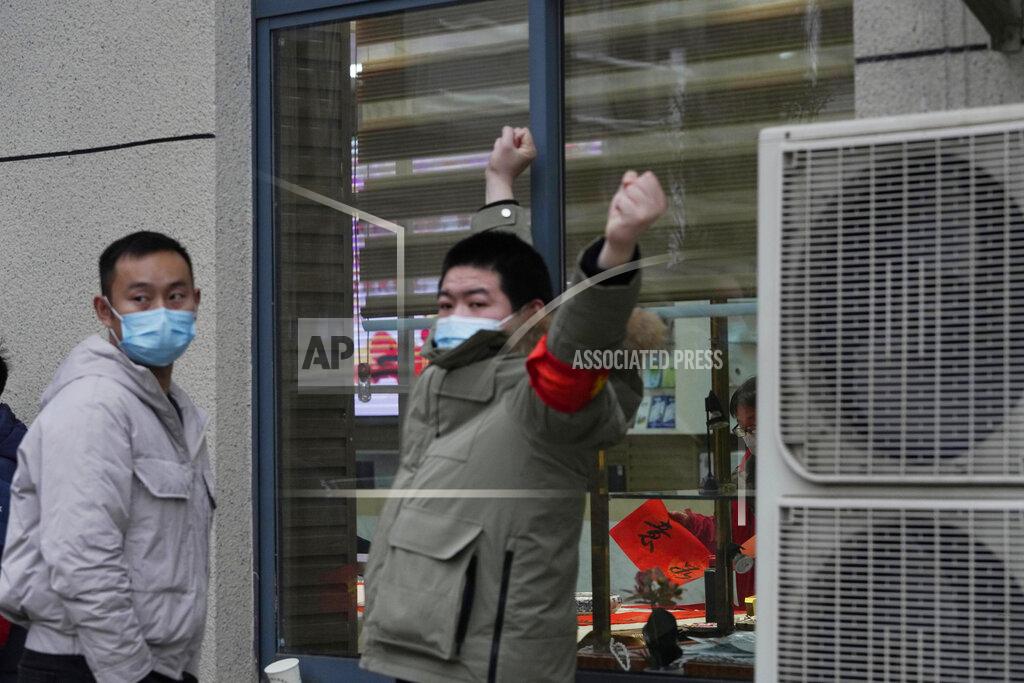 Ng Han Guan Security personnel blocks a window into the Service Center for Party Members and Residents of Jiangxinyuan Community where a World Health Organization team is making a field visit in Wuhan in central China's Hubei province on Thursday, Feb. 4, 2021. (AP Photo/Ng Han Guan)