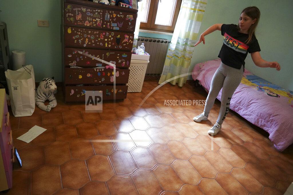 Andrew Medichini Elena Moretti looks at her cellphone as she attends an online dancing lesson, in her bedroom in Rome, Thursday, May 14, 2020 during the COVID-19 coronavirus lockdown. Sometimes the internet connection goes out. But she’s still managed to keep in touch with friends, with some video chats lasting for hours. (AP Photo/Andrew Medichini)
