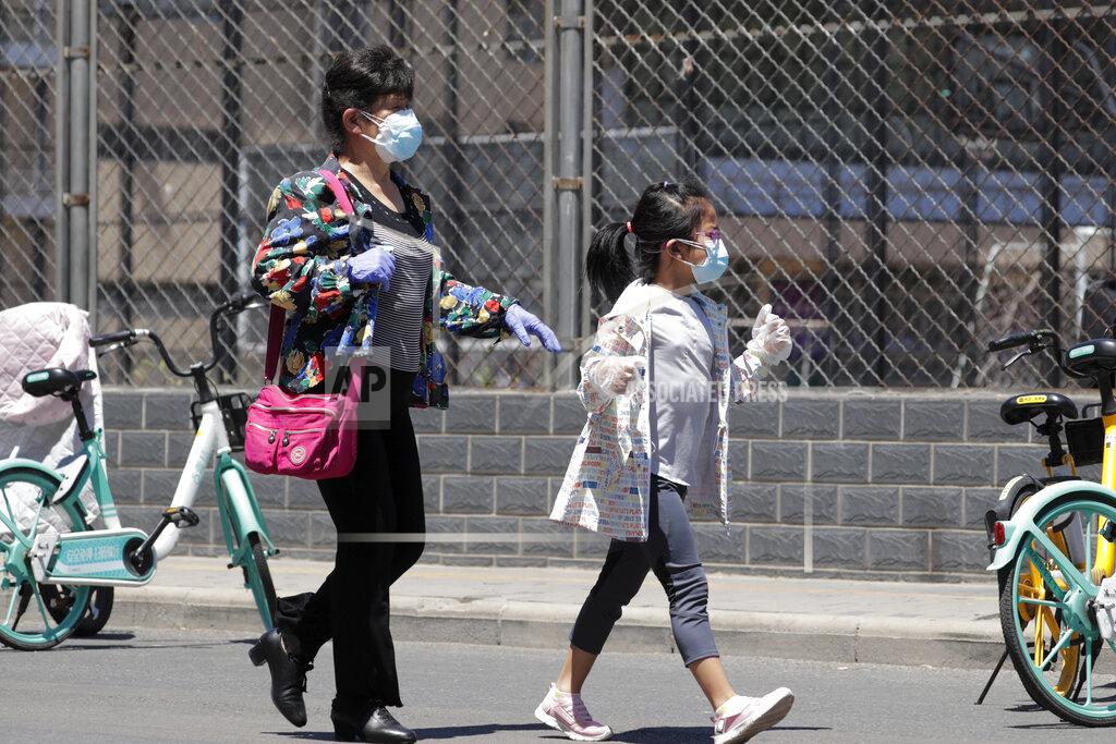 Andy Wong A woman and a child wearing protective face masks and gloves to help curb the spread of the new coronavirus arrive to a stadium to get a nucleic acid test in Beijing, Sunday, June 14, 2020. China is reporting its highest daily total of coronavirus cases in two months after the capital's biggest wholesale food market was shut down following a resurgence in local infections. (AP Photo/Andy Wong)