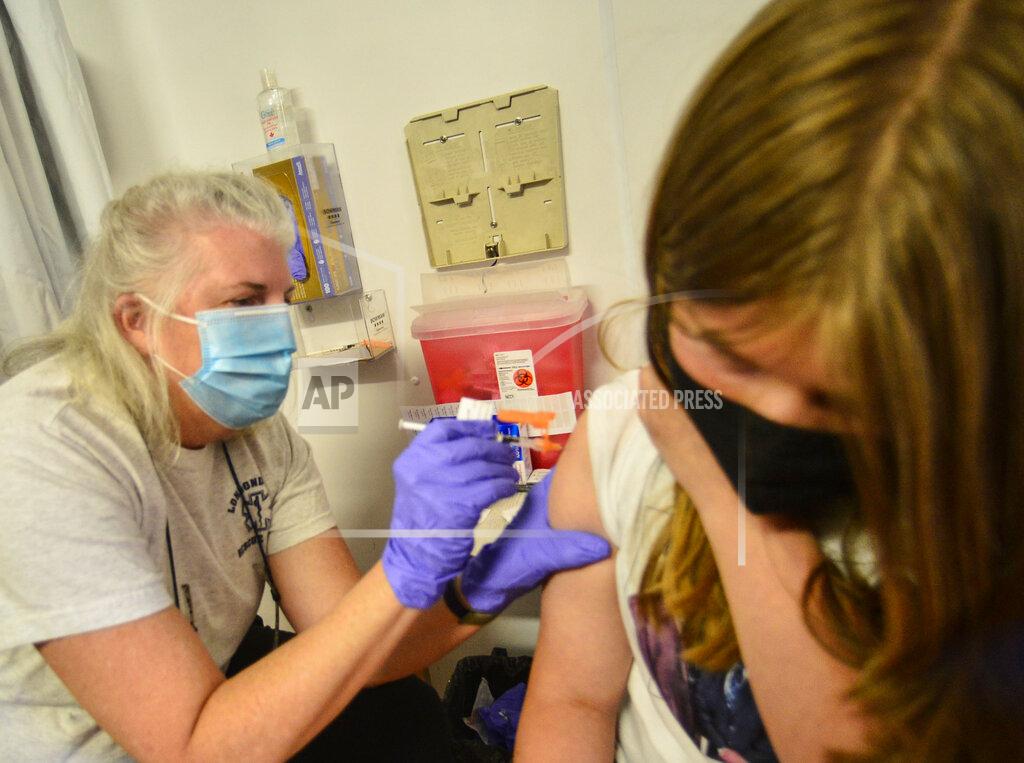 Kristopher Radder Laurie Gayda, a vaccinator with Rescue Inc., gives Lola McGinnis, 12, of Bellows Falls, Vt., the first dose of the Pfizer COVID-19 vaccine as her sister, Lola, 12, waits for her shot on Monday, May 24, 2021. Rescue Inc. hosted a dual COVID-19 vaccine clinic at the Bellows Falls Fire Department, in Bellows Falls, Vt. People could get a scheduled dose of the Pfizer vaccine or go to the walk-in Johnson & Johnson clinic. (Kristopher Radder/The Brattleboro Reformer via AP)