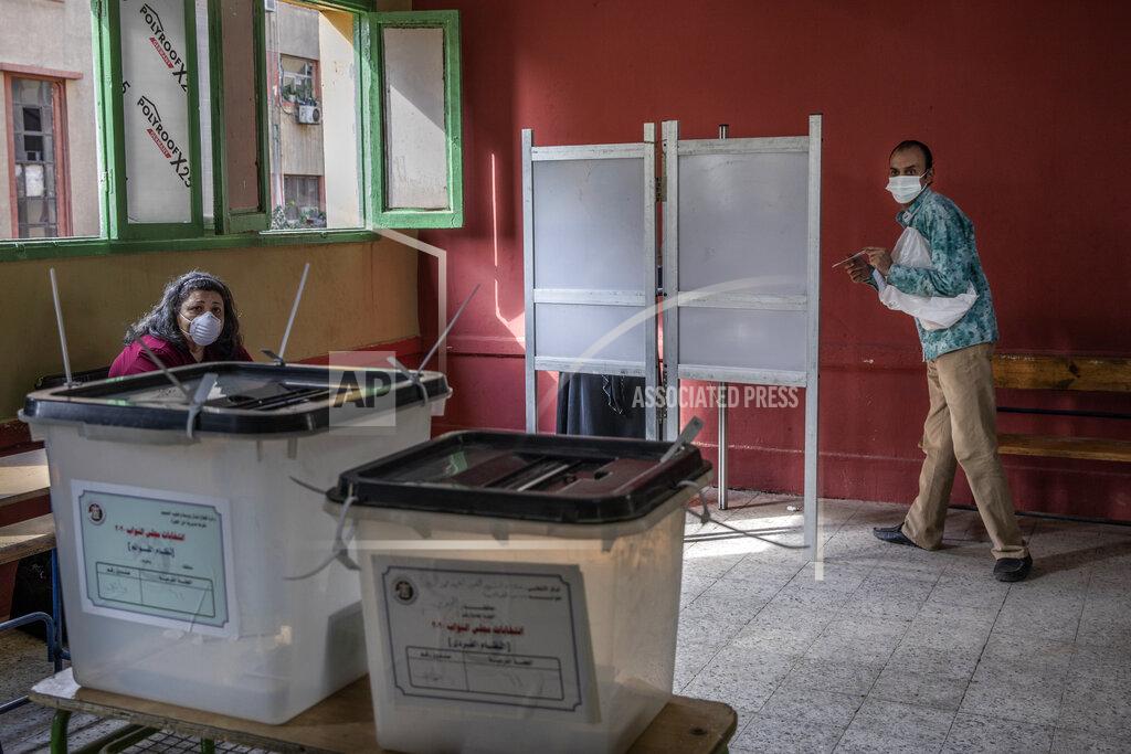 Nariman El-Mofty A man prepares to cast ballot on the first day of the parliamentary election inside a polling station in Giza, Egypt, Saturday, Oct. 24, 2020. Egyptians began voting Saturday in the first stage of a parliamentary election, a vote that is highly likely to produce a toothless House of Representatives packed with supporters of President Abdel-Fattah el-Sissi. (AP Photo/Nariman El-Mofty)