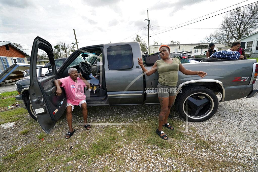 Gerald Herbert Loubertha Rideaux, left, sits on the door jamb of a truck in Lake Charles, La., as her daughter Patricia Mingo Lavergne reacts, after they returned form evacuation in the aftermath of Hurricane Laura, Sunday, Aug. 30, 2020. They evacuated and returned in the truck with eight adults and one child. (AP Photo/Gerald Herbert)