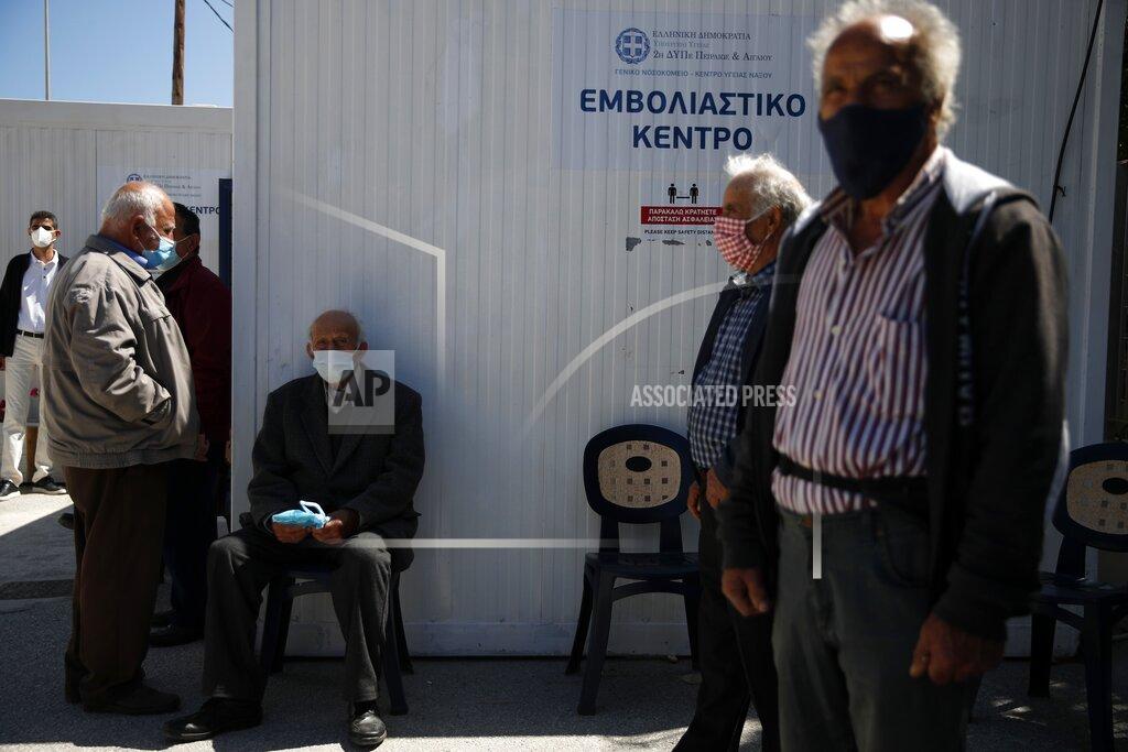 Local residents wearing face masks to help curb the spread of the coronavirus, wait outside a vaccination center on the Aegean island of Naxos, Greece, Tuesday, May 11, 2021. A vaccination program for Greek islands is being accelerated to cover all local residents by the end of June, the government has announced ahead of the launch of the tourism season. (AP Photo/Thanassis Stavrakis)