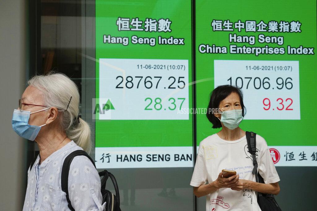 Kin Cheung People wearing face masks stand next to a bank's electronic board showing the Hong Kong share index in Hong Kong, Friday, June 11, 2021. Shares were mostly higher in Asia on Friday after the S&P 500 index notched another record high despite a 5% surge in U.S. consumer prices in May. (AP Photo/Kin Cheung)