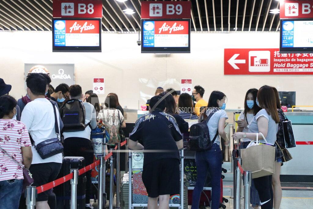 Uncredited Malaysians and Singaporeans stranded in Macao during pandemic, line up at a check-in counter for the special AirAsia flight to Kuala Lumpur, in Macao airport, Thursday, April 8, 2021. About 50 people of various nationalities boarded a chartered flight from Macao to Malaysia on Thursday after many were stranded for months by the pandemic and border restrictions. (AP Photo)