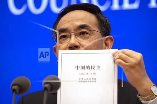 Xu Lin, vice minister of the Publicity Department of the Central Committee of China's Communist Party holds a copy of a government-produced report titled "Democracy that Works" during a press conference at the State Council Information Office in Beijing, Saturday, Dec. 4, 2021. China's Communist Party took American democracy to task on Saturday, sharply criticizing a global democracy summit being hosted by President Joe Biden next week and extolling the virtues of its governing system. (AP Photo/Mark Schiefelbein)