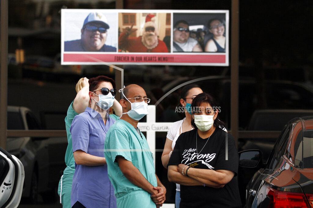 Cedar Attanasio FILE - In this Thursday, May 21, 2020 file photo, mourners wear masks to prevent the spread of COVID-19 at a memorial for Walmart shooting victim Guillermo "Memo" Garcia, in El Paso, Texas. Garcia died after nine months in at Del Sol Medical Center. El Paso is marking the year anniversary of the a shooting at a crowded Walmart by remembering the 23 people killed. Authorities have said the gunman traveled from his home near Dallas to target Latinos in the Texas border city on Aug. 3, 2019. (AP Photo/Cedar Attanasio, File)