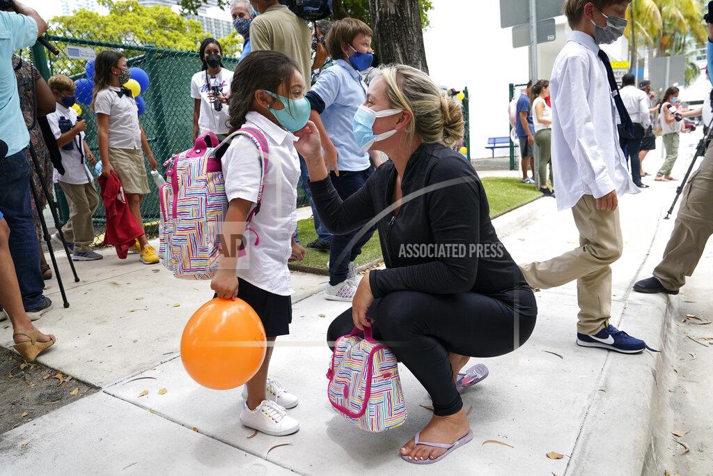 Lynne Sladky Carol Basilio, right, greets her daughter Giovanna, 4, left, outside of iPrep Academy on the first day of school, Monday, Aug. 23, 2021, in Miami. Public schools in Miami-Dade County have a strict mask mandate to guard against coronavirus infections. A Florida judge ruled Wednesday, Sept. 8, that the state cannot enforce a ban on public schools mandating the use of masks to guard against the coronavirus, while an appeals court sorts out whether the ban is ultimately legal. (AP Photo/Lynne Sladky)