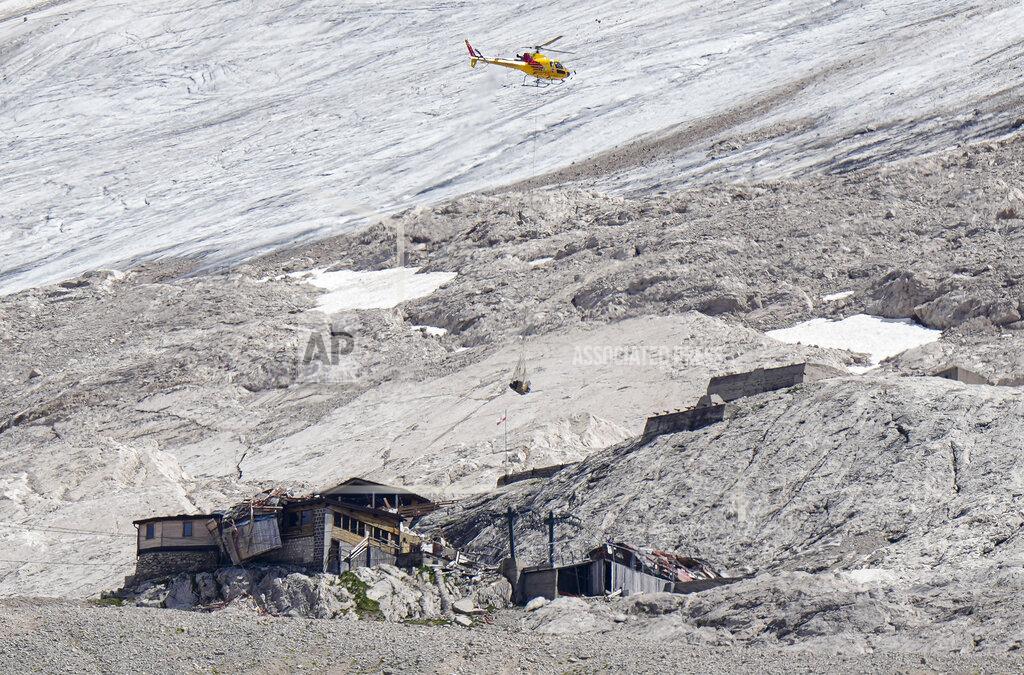 Luca Bruno A rescue helicopter carries technical equipment on the Punta Rocca glacier near Canazei, in the Italian Alps in northern Italy, Tuesday, July 5, 2022, where an avalanche broke loose on Sunday, sending tons of ice, snow, and rocks onto hikers. (AP Photo/Luca Bruno)