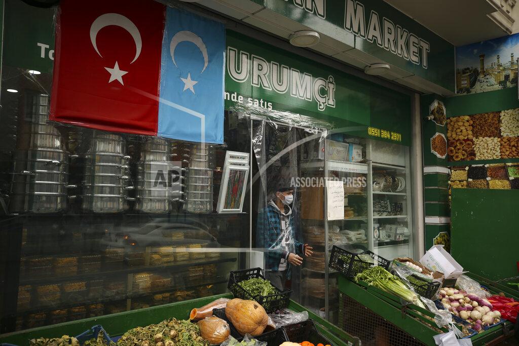 Emrah Gurel A member of the Uighur community leaves a grocery store decorated with a Turkish flag and one of what ethnic Uighurs call 'East Turkestan', in Istanbul's Zeytinburnu neighborhood, Tuesday, Feb. 2, 2021. Because of shared cultural ties, Turkey has long been a safe haven for the Uighurs, a Turkic group native to China's far west Xinjiang region. Opposition legislators in Turkey are accusing Ankara's leaders of secretly selling out Uighurs to China in exchange for coronavirus vaccines.(AP Photo/Emrah Gurel)