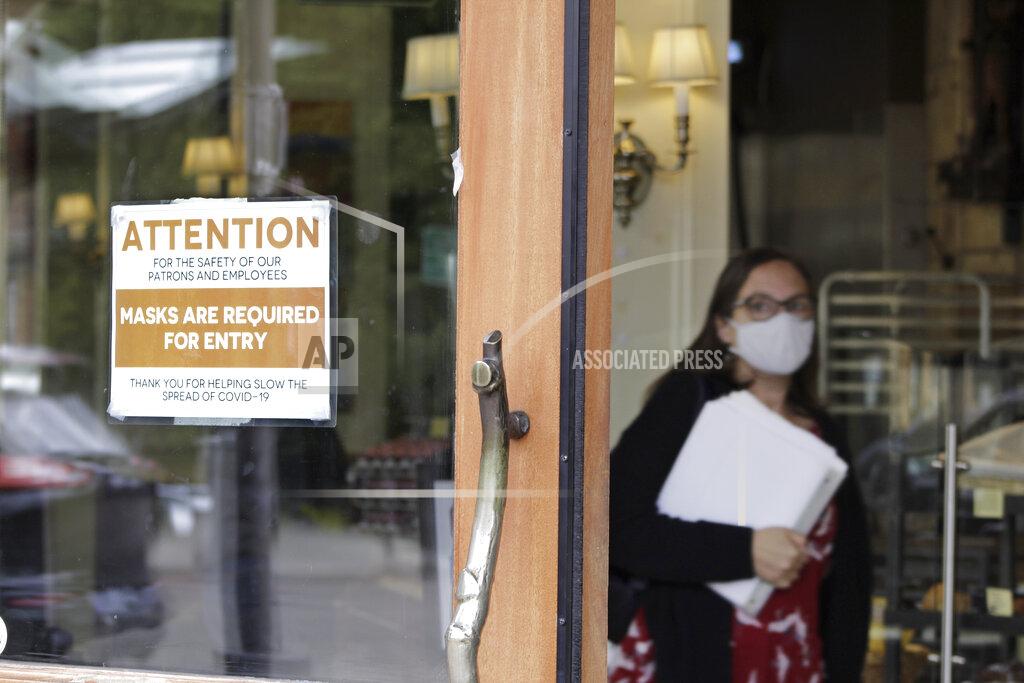 Gillian Flaccus A sign reminds customers to wear their masks at a bakery in Lake Oswego, Ore., on Friday, May 21, 2021. As the federal government and many states ease rules around mask-wearing and business occupancy, some blue states like Oregon and Washington are still holding on to some longtime coronavirus restrictions. (AP Photo/Gillian Flaccus)