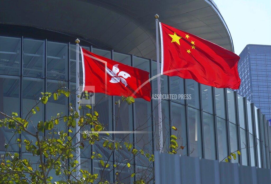 Vincent Yu FILE - In this April 13, 2021, file photo, China's national flag, right, and Hong Kong's flag flutter at the Legislative Council in Hong Kong. Hong Kong's polls for an election committee that will vote for the city's leader kicked off Sunday amid heavy police presence, with chief executive Carrie Lam saying that it is "very meaningful" as it is the first election to take place following electoral reforms. (AP Photo/Vincent Yu, File)
