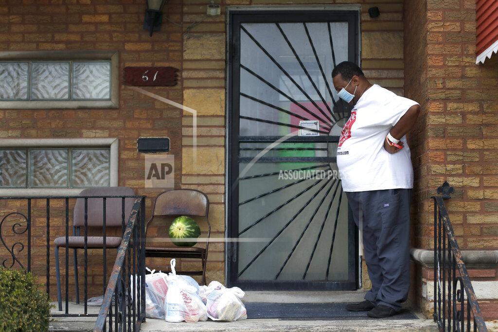 Charles Rex Arbogast Anthony Travis, who has recovered from COVID-19 and lives with his sister and an adult daughter, looks at a surprise anonymous delivery of groceries on the porch of his Riverdale, Ill., home on Thursday, April 23, 2020. Travis, who's diabetic, has high blood pressure and is a cancer survivor, must self isolate within the home as a matter of taking care of one another. (AP Photo/Charles Rex Arbogast)