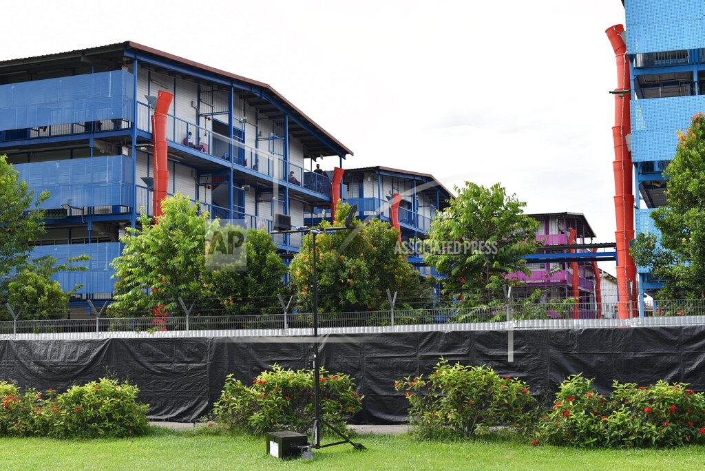Yk Chan In this Sunday, May 10, 2020, photo, people sit outside a building balcony at the S11@Punggol, a complex of dormitory buildings for foreign workers in Singapore. A second wave of coronavirus infections in tightly packed foreign workers' dormitories has caught Singapore off guard, and exposed the danger of overlooking marginal groups in a health crisis. (AP Photo/YK Chan)