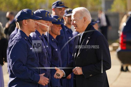 President Joe Biden hands out a challenge coin as he speaks with members of the coast guard at the United States Coast Guard Station Brant Point in Nantucket, Mass., Thursday, Nov. 25, 2021. (AP Photo/Carolyn Kaster)