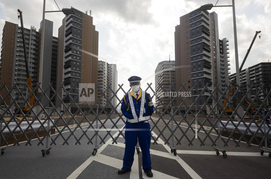 Hiro Komae A guard stands in front of a fence to close off a construction site for the athletes' village to be used during the postponed Tokyo 2020 Olympic and Paralympic Games, in Tokyo Thursday, April 8, 2021. Many preparations are still up in the air as organizers try to figure out how to hold the postponed games in the middle of a pandemic. (AP Photo/Hiro Komae)