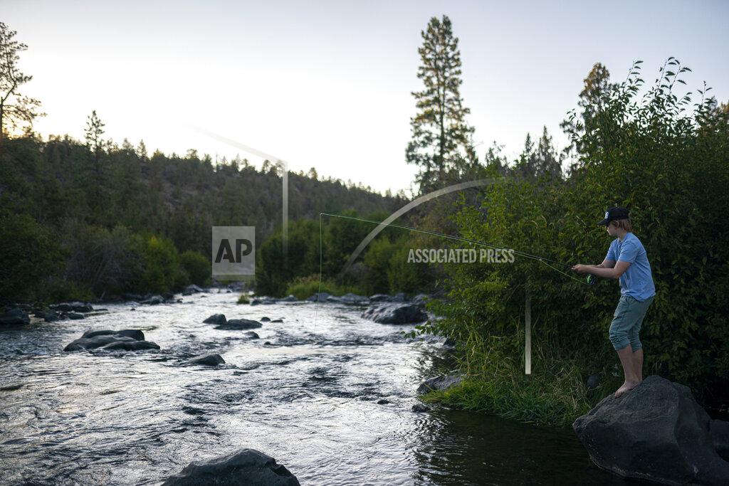 Nathan Howard Arbor Bennet fly fishes along Deschutes River on Tuesday, Aug. 31, 2021, in Bend, Ore. In this fertile swath of central Oregon, where six irrigation districts rely on the river, the consequences of the strict hierarchy dictated by the American West's arcane water law — "first in time, first in right" — are written on the land. (AP Photo/Nathan Howard)