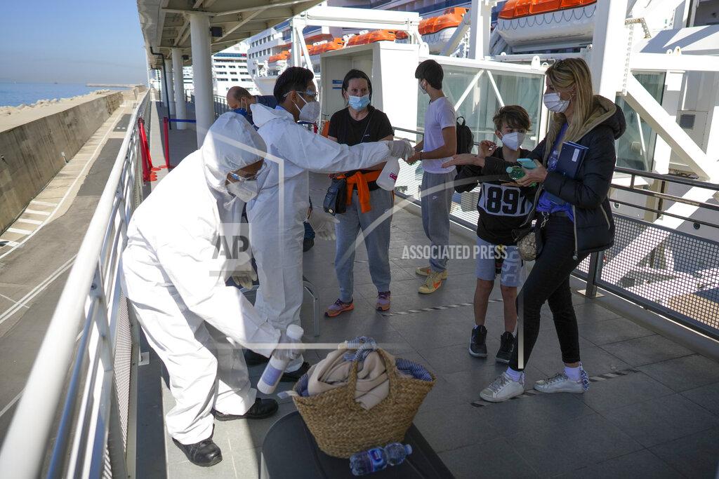 Andrew Medichini Passengers, from right, Stefania Battistoni, her sons Dasteen and Samuel Pacifici and her mother Loredana Merlo have their hand luggage sanitized prior to boarding the MSC Grandiosa cruise ship in Civitavecchia, near Rome, Wednesday, March 31, 2021. MSC Grandiosa, the world's only cruise ship to be operating at the moment, left from Genoa on March 30 and stopped in Civitavecchia near Rome to pick up more passengers and then sail toward Naples, Cagliari, and Malta to be back in Genoa on April 6. For most of the winter, the MSC Grandiosa has been a lonely flag-bearer of the global cruise industry stalled by the pandemic, plying the Mediterranean Sea with seven-night cruises along Italy’s western coast, its major islands and a stop in Malta. (AP Photo/Andrew Medichini)