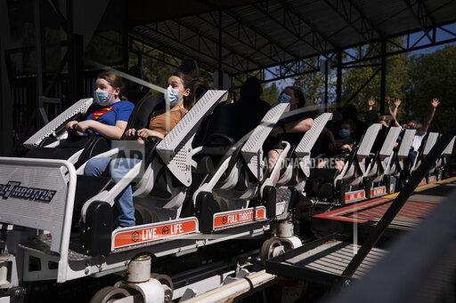 Two children wearing face masks react as a roller coaster departs a station at Six Flags Magic Mountain on its first day of reopening to members and pass holders in Valencia, Calif., Thursday, April 1, 2021. The theme park had been closed since March 2020 due to the coronavirus pandemic. (AP Photo/Jae C. Hong)