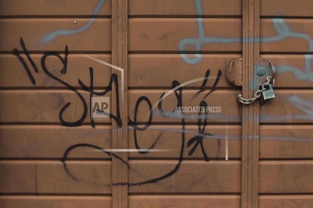 Salvador Melendez A padlock and chain provides an extra layer of protection on an already locked garage door reportedly tagged by gang members, in Santa Ana, El Salvador, Saturday, Aug. 22, 2020. After years of waiting in countries marred by violence, Central Americans who were approved to come to the U.S. through a small refugee program are facing a major obstacle: the new coronavirus pandemic. (AP Photo/Salvador Melendez)