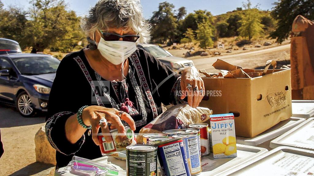 Travis Robertson Oracle Community Center board member Elvia Schwenke sorts food on Feb. 26, 2021, for the Little Free Pantry in Oracle, Ariz. Oracle launched the project in September as a part of the Little Free Pantry movement, one of several efforts worldwide in which people donate food and goods and house them in a neighborhood space to be used by anyone who needs help. (Travis Robertson/Cronkite News via AP)