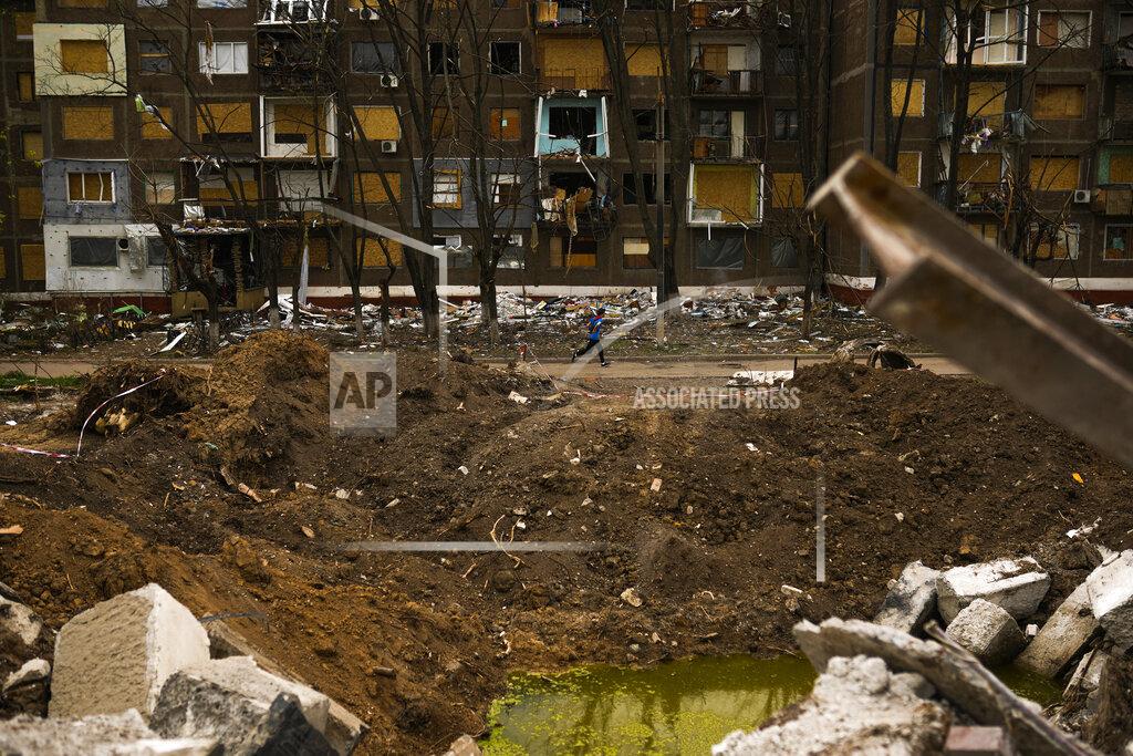 Francisco Seco A young local resident passes by a crater caused by a Russian strike earlier in May opposite an apartment building in Kramatorsk, eastern Ukraine, Saturday, May 21, 2022. (AP Photo/Francisco Seco)