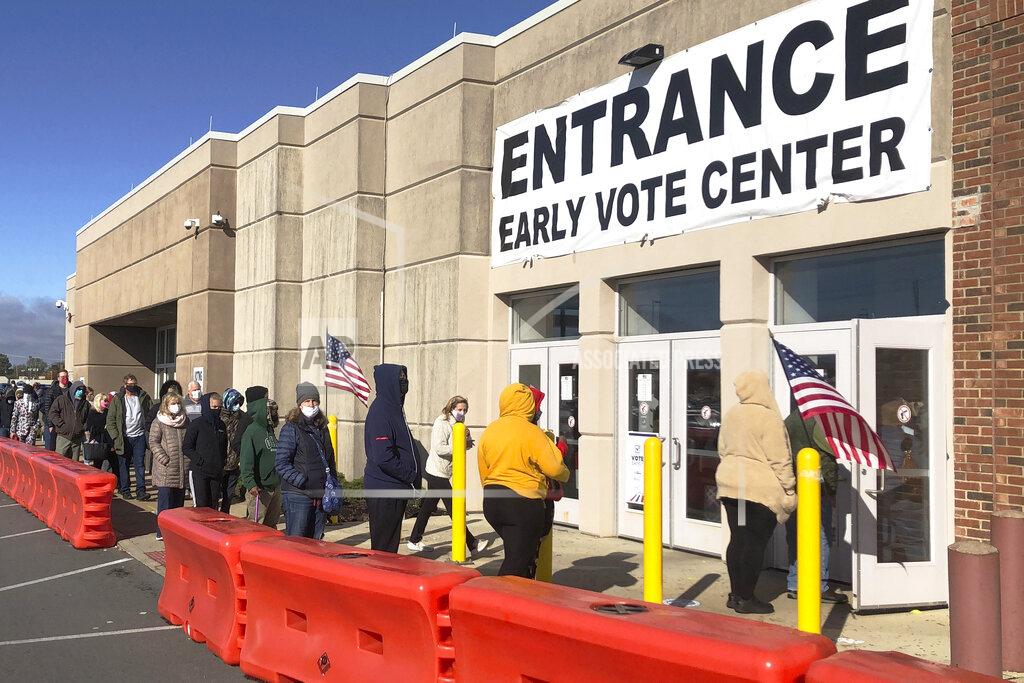 Andrew Welsh Huggins FILE — In this Oct. 30, 2020 file photo, people bundled against the cold stand in a slowly moving line to cast early votes at the Franklin County Board of Elections, in Columbus, Ohio. (AP Photo/Andrew Welsh-Huggins, FIle)