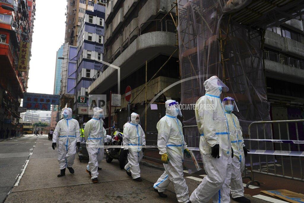 Vincent Yu Cleaners wearing protective suits, gather in the Yau Ma Tei area, in Hong Kong, Saturday, Jan. 23, 2021. Thousands of Hong Kong residents were locked down Saturday in an unprecedented move to contain a worsening outbreak in the city, authorities said. (AP Photo/Vincent Yu)