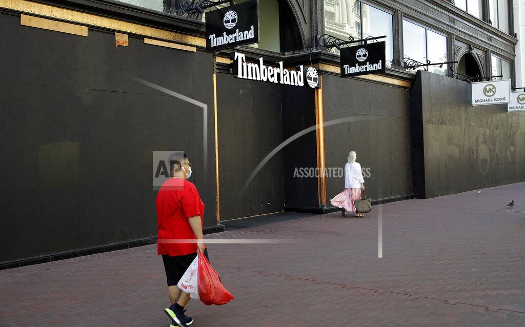 Ben Margot Masked people walk past a boarded up Timberland clothing store, Wednesday, May 27, 2020, in San Francisco. While much of California moves swiftly to reopen things like hair salons under Gov. Gavin Newsom's guidance, the San Francisco Bay Area is continuing to keep the brakes on. Some health officials are questioning whether the state is taking enough time to assess the effects of reopening things like stores before jumping ahead to broader re-openings, risking a surge in infections. (AP Photo/Ben Margot)