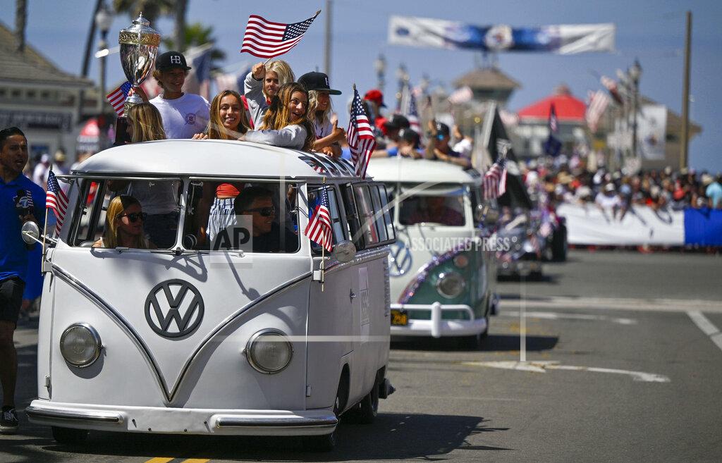 Jeff Gritchen Members of the National Scholastic Surfing Association ride up Main Street during the 118th Huntington Beach 4th of July in Huntington Beach, Calif., on Monday, July 4, 2022. (Jeff Gritchen/The Orange County Register via AP)