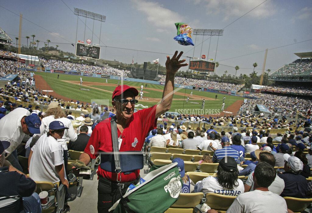 Branimir Kvartuc FILE - In this April 9, 2007, file photo, peanut vendor Richard Aller tosses a bag to a buyer during the Los Angeles Dodgers home opener baseball game against the Colorado Rockies in Los Angeles. Most teams and leagues are reticent to discuss the financial impact from the coronavirus pandemic. There's a loss that's going to take place industry-wise. It's simply unavoidable,” said Marc Ganis, the co-founder of Chicago-based consulting firm SportsCorp. “If they can come back, they can reduce the loss for the players, the coaches, the people who work the ticket booths. The ushers, the security people, the parking lot attendants and concessionaires. All of these people — thousands for a football game or baseball game. These are the people that need money, who need to work.” (AP Photo/Branimir Kvartuc, File)