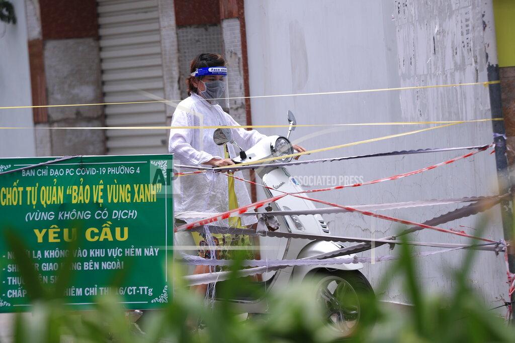 Hau Dinh A woman stops her scooter as the alley is blocked with cordon tapes in Vung Tau, Vietnam, Monday, Sept. 13, 2021. The roadblocks and barricades make the streets of this southern Vietnamese city look like they did during the war that ended almost 50 years ago. But this time, the battle is being fought against the rampaging coronavirus.(AP Photo/Hau Dinh)