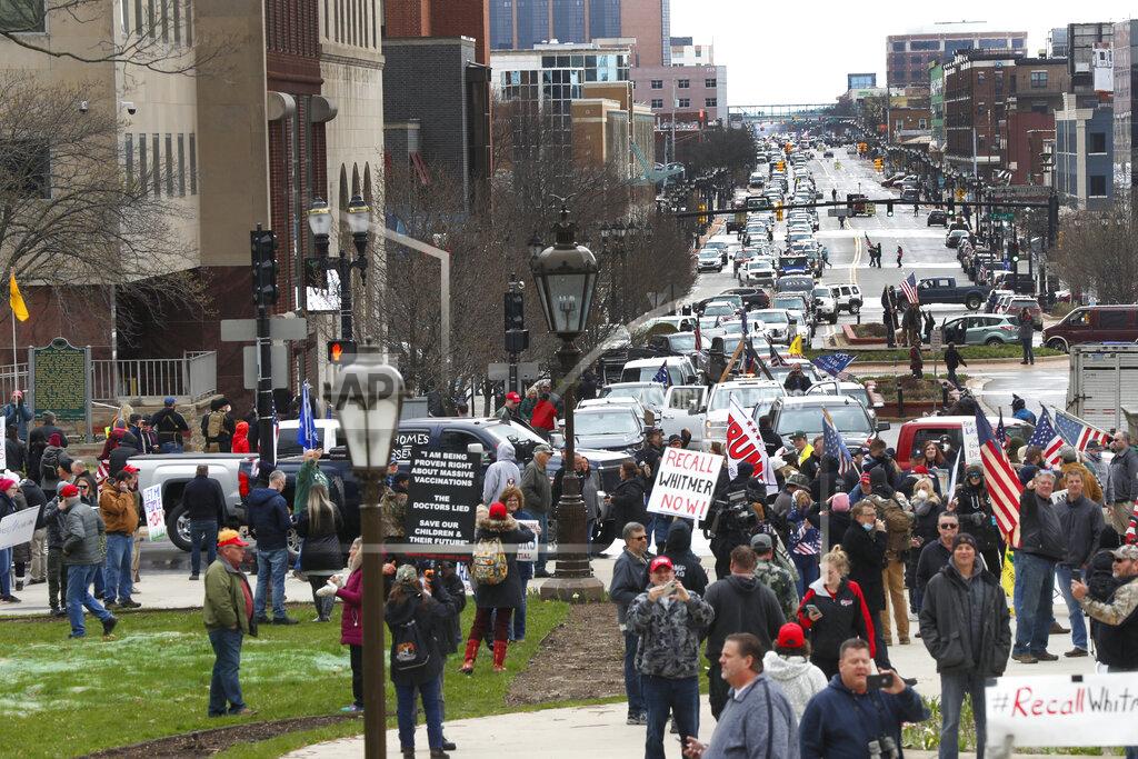 Paul Sancya Protesters gather at the Michigan State Capitol in Lansing, Mich., Wednesday, April 15, 2020. Flag-waving, honking protesters drove past the Michigan Capitol on Wednesday to show their displeasure with Gov. Gretchen Whitmer's orders to keep people at home and businesses locked during the new coronavirus COVID-19 outbreak. (AP Photo/Paul Sancya)