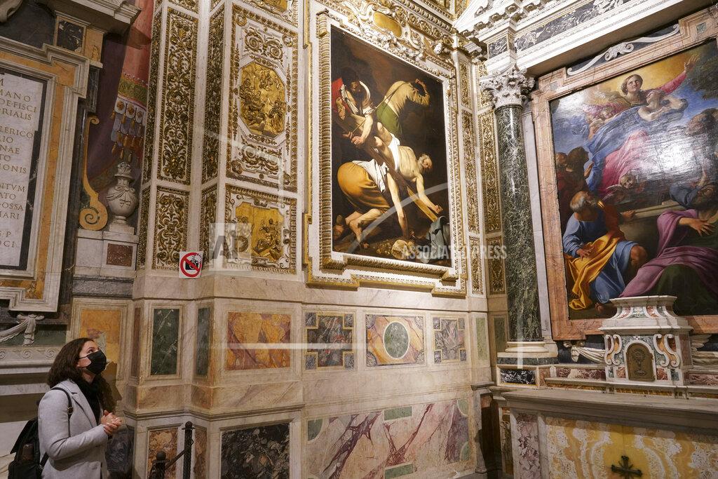 Andrew Medichini A woman wearing a face mask to curb the spread of COVID-19 admires paintings he Cerasi Chapel of Santa Maria del Popolo church, Rome, Friday, Dec. 11, 2020. At left is "The Crucifixion of St. Peter", 1601, by Renaissance master Michelangelo Merisi, known as Caravaggio, and at right, "The Assumption of the Virgin", 1601, by Annibale Carracci. Like elsewhere in Europe, museums and art galleries in Italy were closed this fall to contain the spread of COVID-19, meaning art lovers must rely on virtual tours to catch a glimpse of the treasures held by famous institutions such as the Uffizi in Florence and the Vatican Museums in Rome. However, some exquisite gems of Italy's cultural heritage remain on display in real life inside the country's churches, some of which have collections of renaissance art and iconography that would be the envy of any museum. (AP Photo/Andrew Medichini)