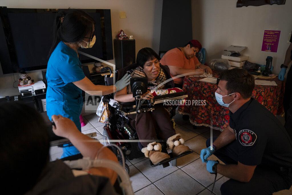 Jae C. Hong Pharmacist Stella Kim, left, and Torrance firefighter Trevor Borello, right, talk with Barbara Franco, who has muscular dystrophy, before administering the second dose of the Pfizer COVID-19 vaccine at her apartment, Wednesday, May 12, 2021, in Torrance, Calif. Teamed up with the Torrance Fire Department, Torrance Memorial Medical Center started inoculating people at home in March, identifying people through a city hotline, county health department, senior centers and doctor's offices, said Mei Tsai, the pharmacist who coordinates the program. (AP Photo/Jae C. Hong)