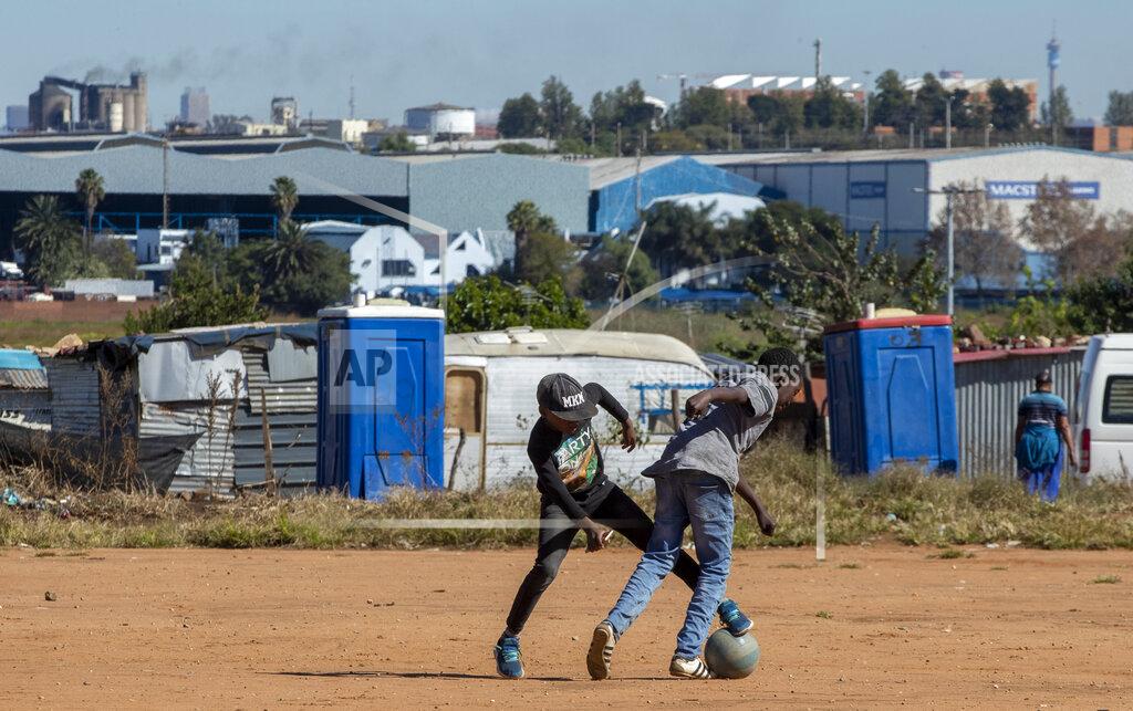 Themba Hadebe Young boys play soccer on a dusty field at Ramaphosa informal settlement, east of Johannesburg, South Africa, Tuesday, April 28, 2020. South Africa will begin a phased easing of its strict lockdown measures on May 1, although confirmed cases of coronavirus continue to increase. (AP Photo/Themba Hadebe)