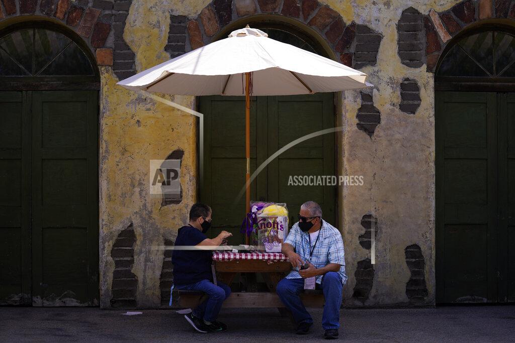 Jae C. Hong Two visitors rest on a picnic table during the Knott's Taste of Boysenberry Festival at Knott's Berry Farm in Buena Park, Calif., Tuesday, March 30, 2021. Massive Los Angeles County can reopen even more businesses, California public health officials announced Tuesday. The county of 10 million people was one of several counties, including neighboring Orange County, that moved into the state's second-least restrictive orange tier amid low coronavirus case rates. (AP Photo/Jae C. Hong)