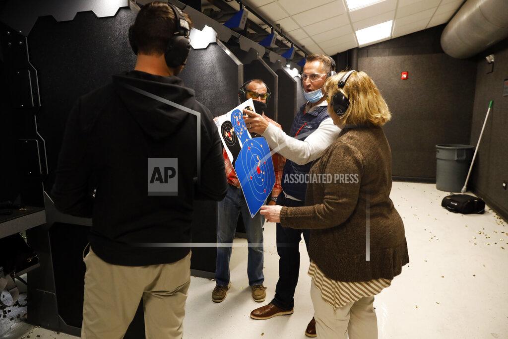Shafkat Anowar Chicago resident Ray Mandel, center, shows his target to others during a shooting session at Maxon Shooter's Supplies and Indoor Range, Friday, April 30, 2021, in Des Plaines, Ill. After a year of pandemic lockdowns, mass shootings are back, but the guns never went away. As the U.S. inches toward a post-pandemic future, guns are arguably more present in the American psyche and more deeply embedded in American discourse than ever before. The past year's anxiety and loss fueled a rise in gun ownership across political and socio-economic lines. (AP Photo/Shafkat Anowar)