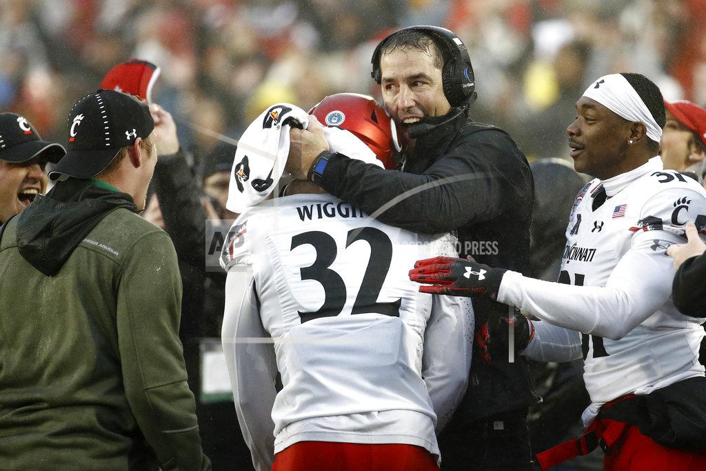 Patrick Semansky Cincinnati head coach Luke Fickell, second from right, embraces safety James Wiggins (32) after Wiggins intercepted a pass attempt in the final moments of the Military Bowl NCAA college football game against Virginia Tech, Monday, Dec. 31, 2018, in Annapolis, Md. Cincinnati won 35-31. (AP Photo/Patrick Semansky)