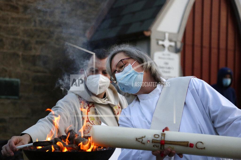 Jessie Wardarski The Reverend Noah Evans helps Deacon Jean Chess light the Paschal candle during St. Paul's Episcopal Church's Easter sunrise service, held on the burial grounds outside of Old St. Luke's Church in Carnegie, Pa., on Sunday, April 4, 2021. For many congregants, this was the first in-person worship service they have attended since the coronavirus surge in November. (AP Photo/Jessie Wardarski)
