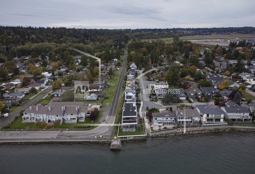 Darryl Dyck Homes in Delta, British Columbia, left, and Point Roberts, Wash., right, are separated by the Canada-U.S. border which is just north of Roosevelt Way in Point Roberts, as seen in an aerial view on Wednesday, Oct. 13, 2021. Point Roberts sits on a peninsula and is only accessible by land by travelling through Canada. Beleaguered business owners and families separated by COVID-19 restrictions rejoiced Wednesday after the U.S. said it will reopen its land borders to nonessential travel next month, ending a 19-month freeze. (Darryl Dyck/The Canadian Press via AP)