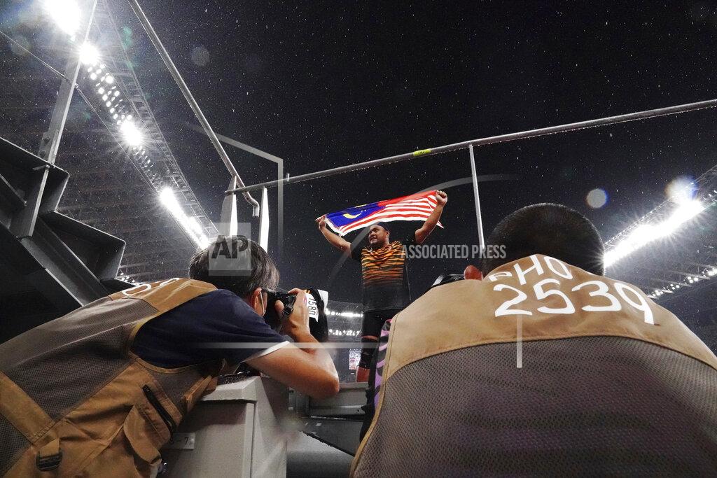 Eugene Hoshiko Photographers take pictures as Muhammad Ziyad Zolkefli of Malaysia reacts after competing in the men's shot put F20 final during the Tokyo 2020 Paralympics Games at the National Stadium in Tokyo, Japan Tuesday, Aug. 31, 2021. Zolkefli appeared to have won gold in the shot put in the F20 class. But after the victory on Tuesday, he was disqualified because he had shown up late for the competition. (AP Photo/Eugene Hoshiko)